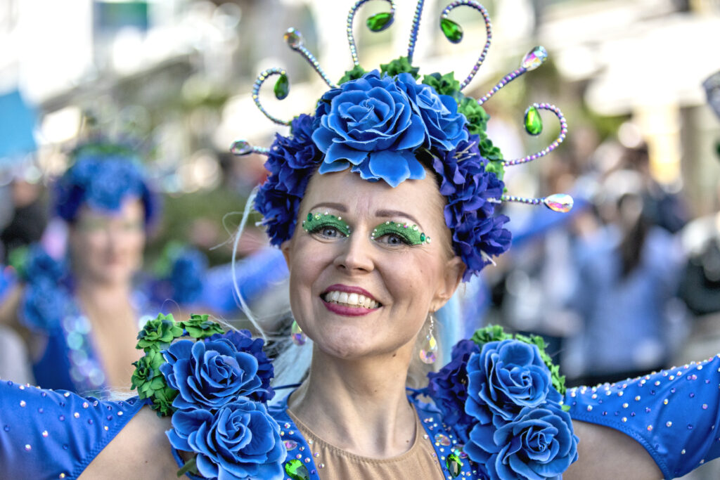 Sambatanssija, nainen, jolla päällä sinisen värinen samba-asu. Kasvokuva, hymyilevät kasvot. 